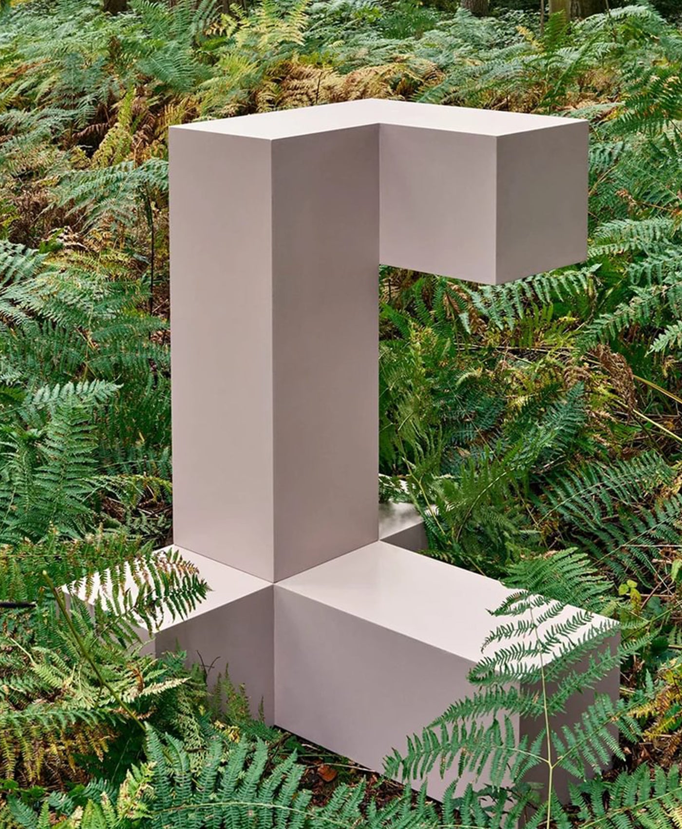 Geometric sculpture painted in plaster coloured paint in a forest setting