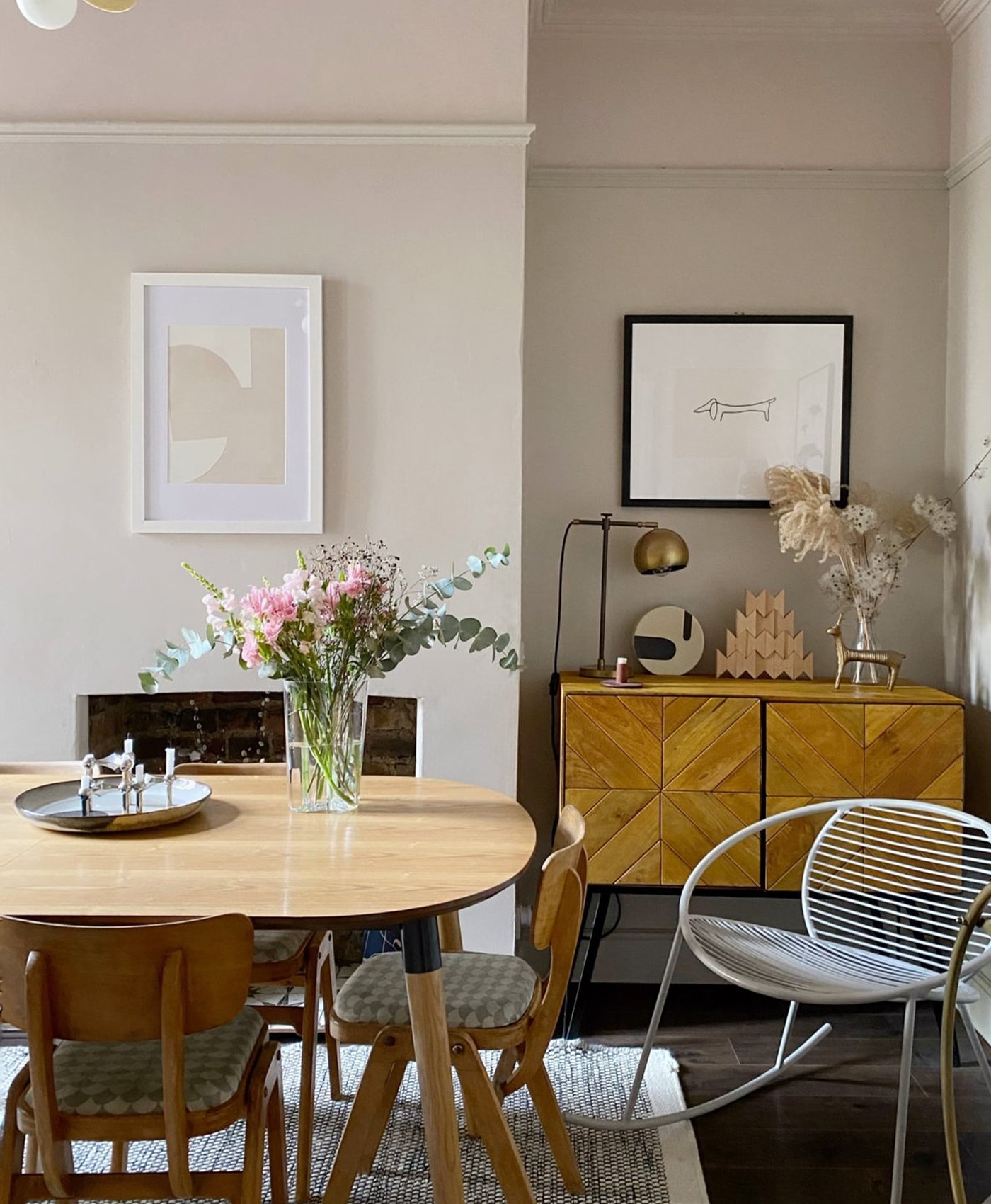 Plaster coloured dining room with wooden table, chairs, and a sideboard with decorative items.