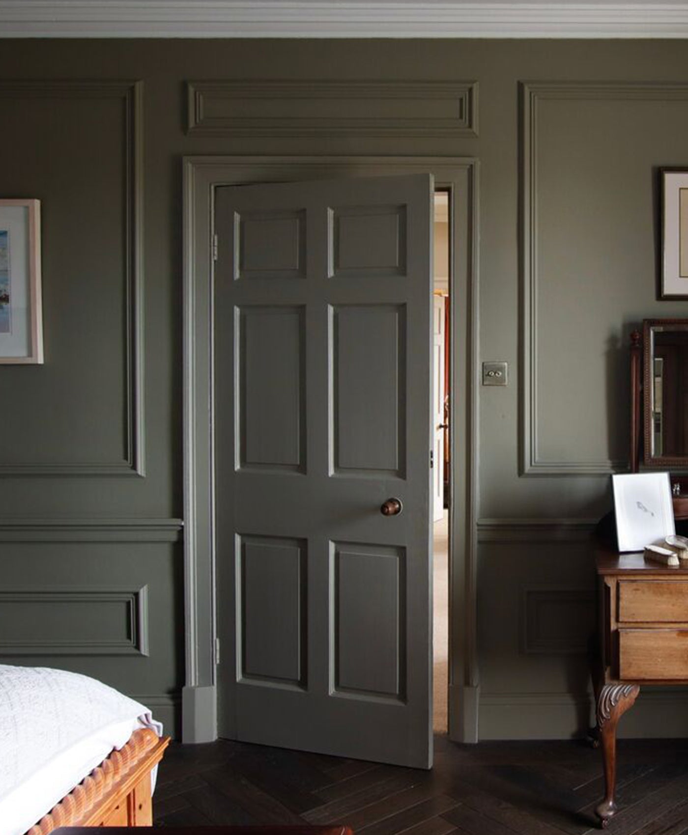 green grey door in a colour drenched room with wooden furniture and framed pictures.