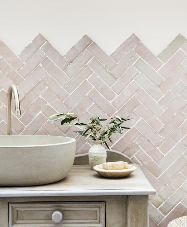 Bathroom vanity with a herringbone tile backsplash and pale pink painted wall