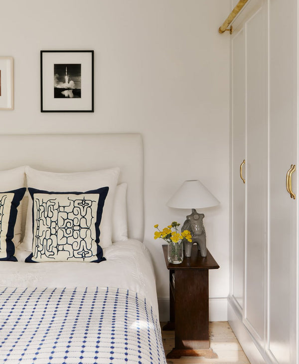 bed with decorative pillows in a pale neutral bedroom setting.