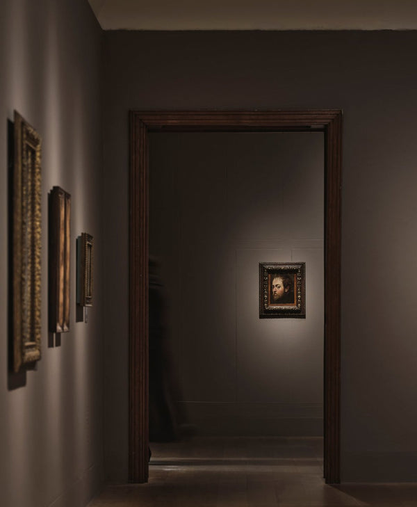 Art gallery with framed paintings on dimly lit walls painted in earthy brown paint