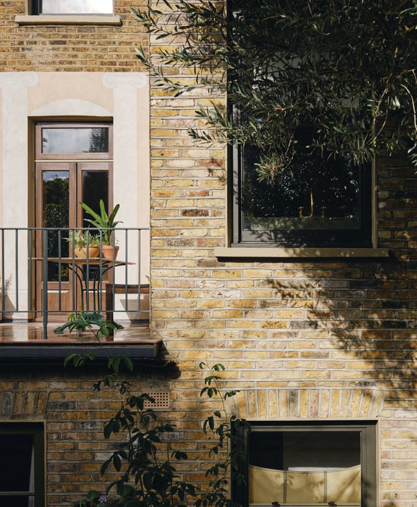 Brick building exterior with plants and window frames painted in warm black paint 