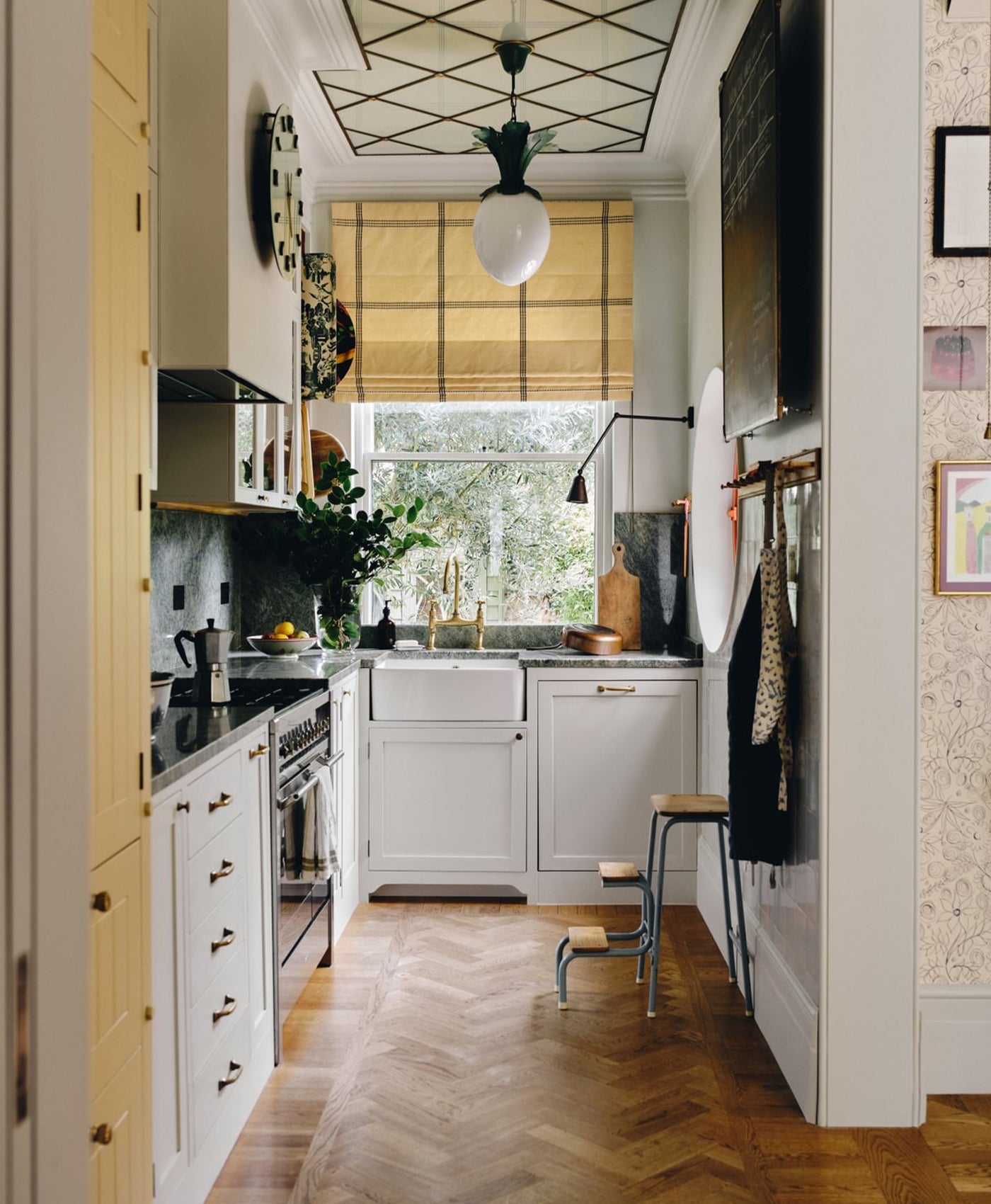 Modern kitchen with cool white cabinets, wooden floor, and large window.