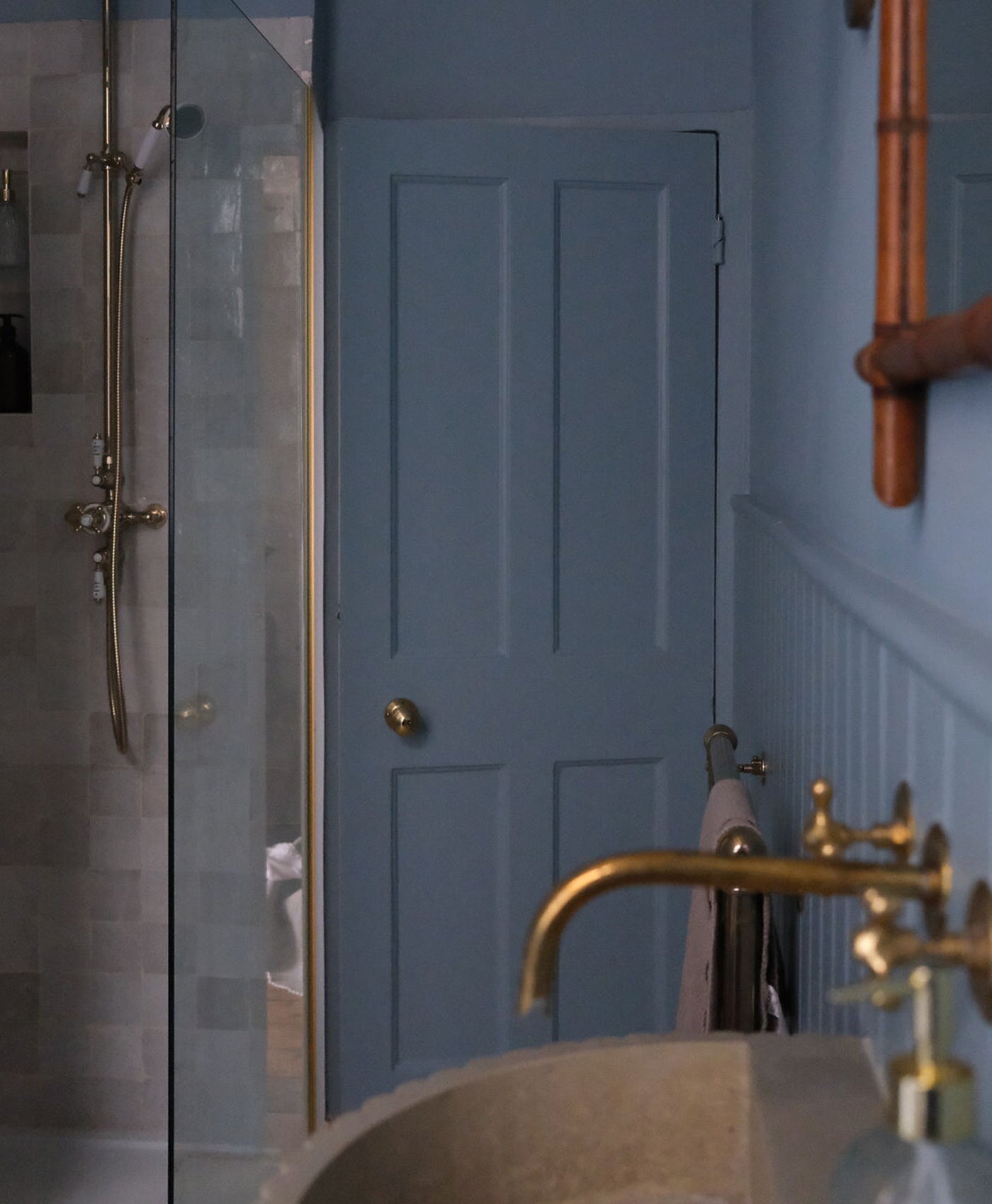 Bathroom with blue door, gold fixtures, and a shower area.