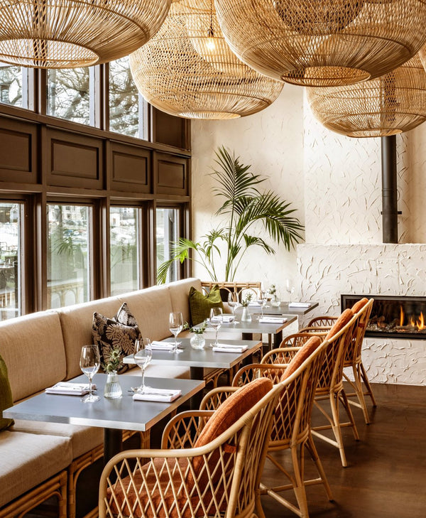 Modern restaurant interior painted inna neutral paint with wicker chairs, tables, and decorative elements.