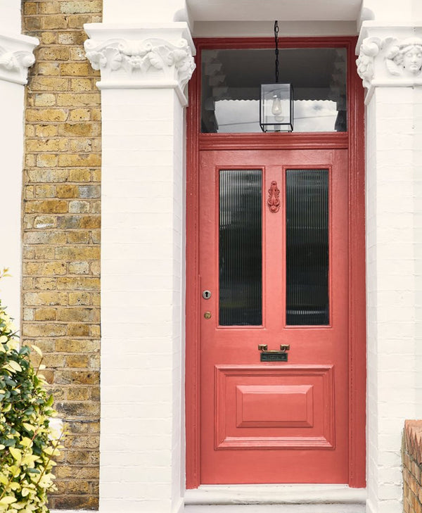 Red front door with glass panels on a brick building