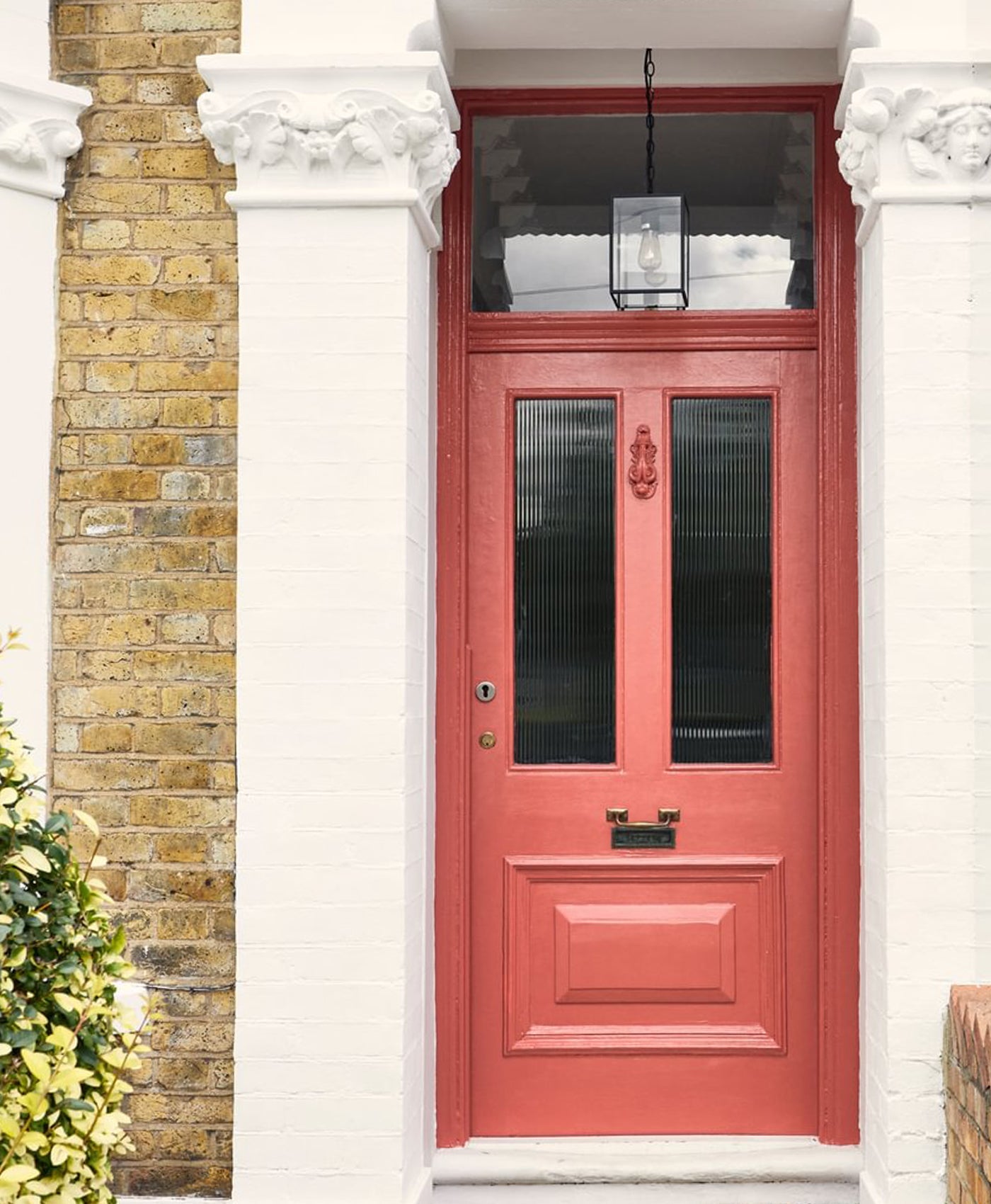 Red front door with glass panels on a brick building