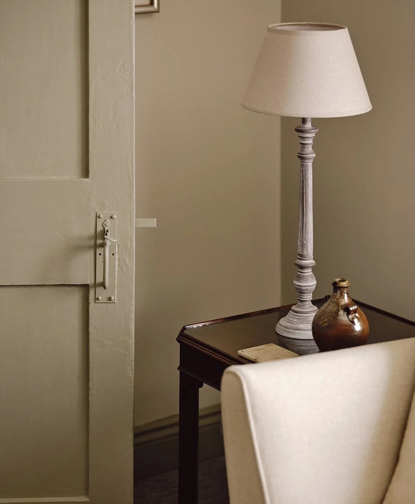 Floor lamp on a side table next to a sofa in a room with neutral walls.