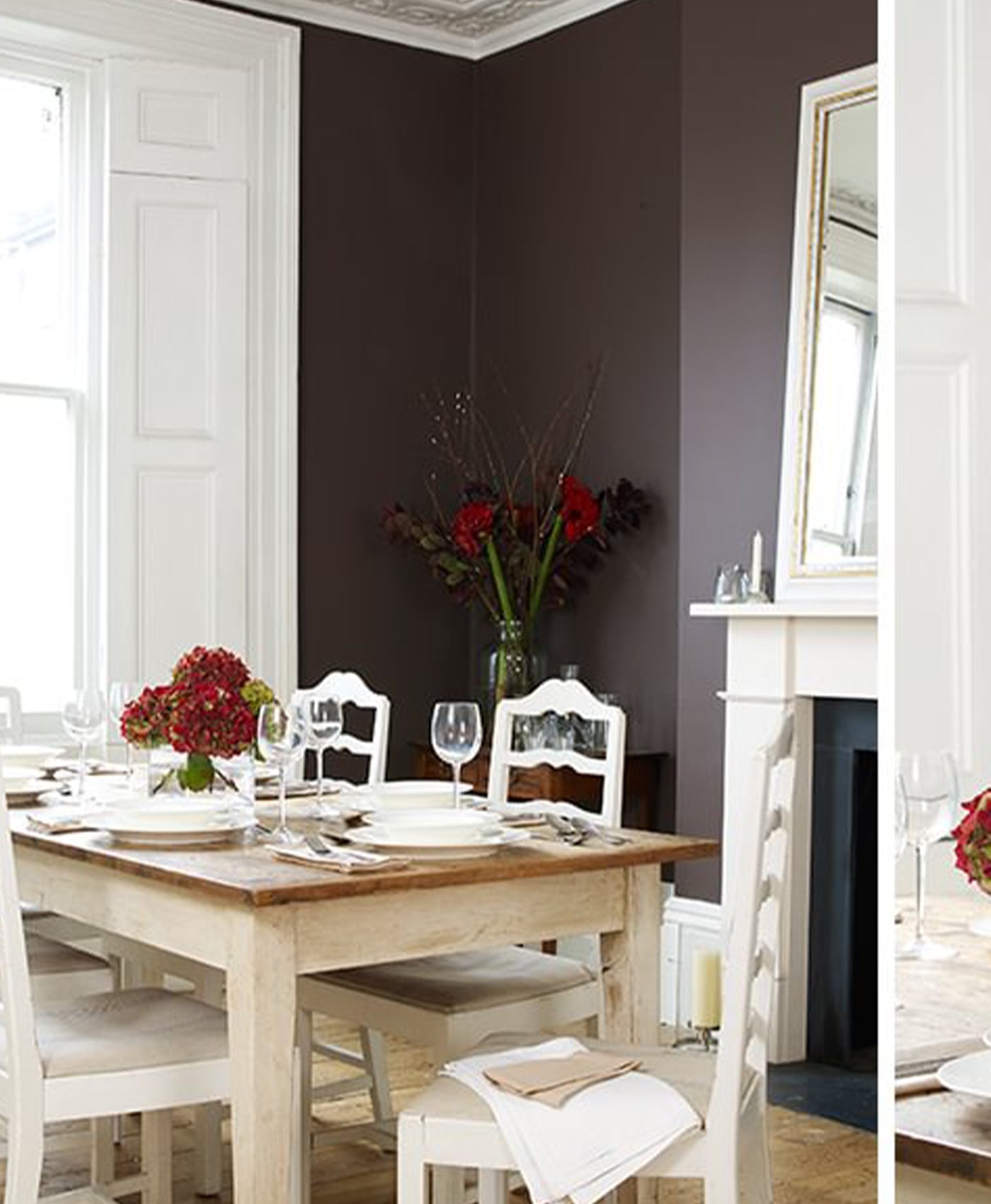 Dining room with a wooden table set for a meal, white chairs, and dark plum coloured walls.