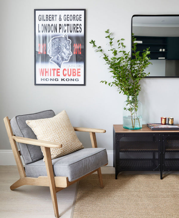 Modern pale grey living room with a chair, plant, and artwork on the wall.