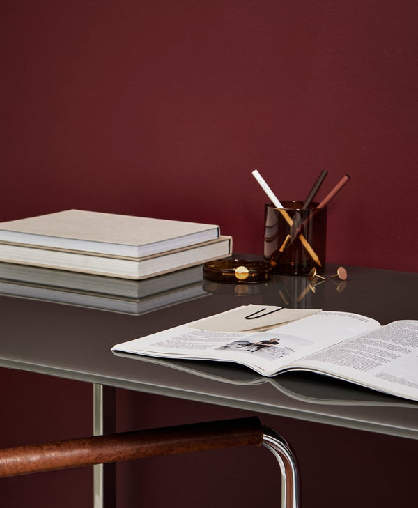 Open book on a desk with stationery against a crimson red wall