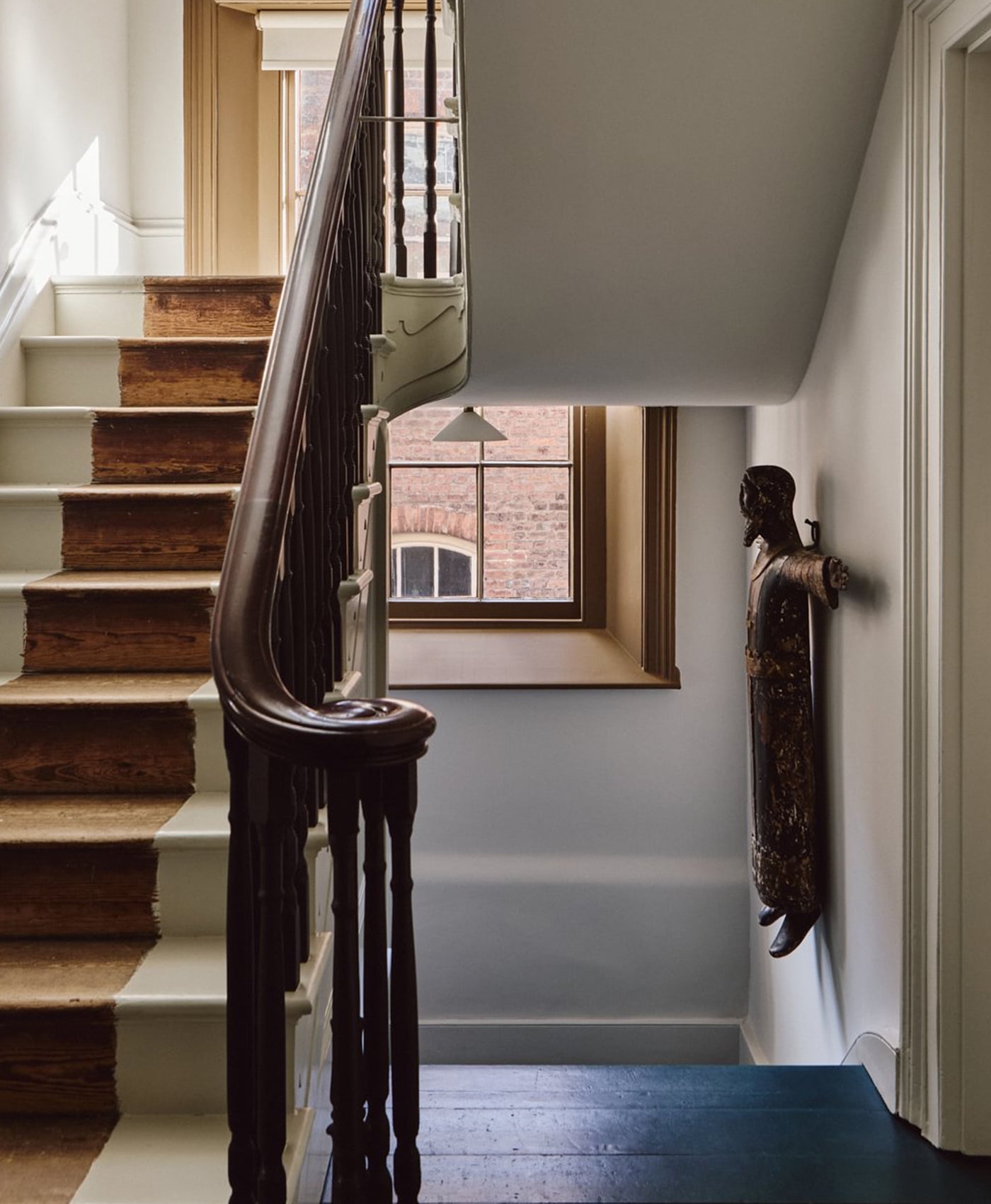 Staircase with wooden handrail leading to a window in a home interior.