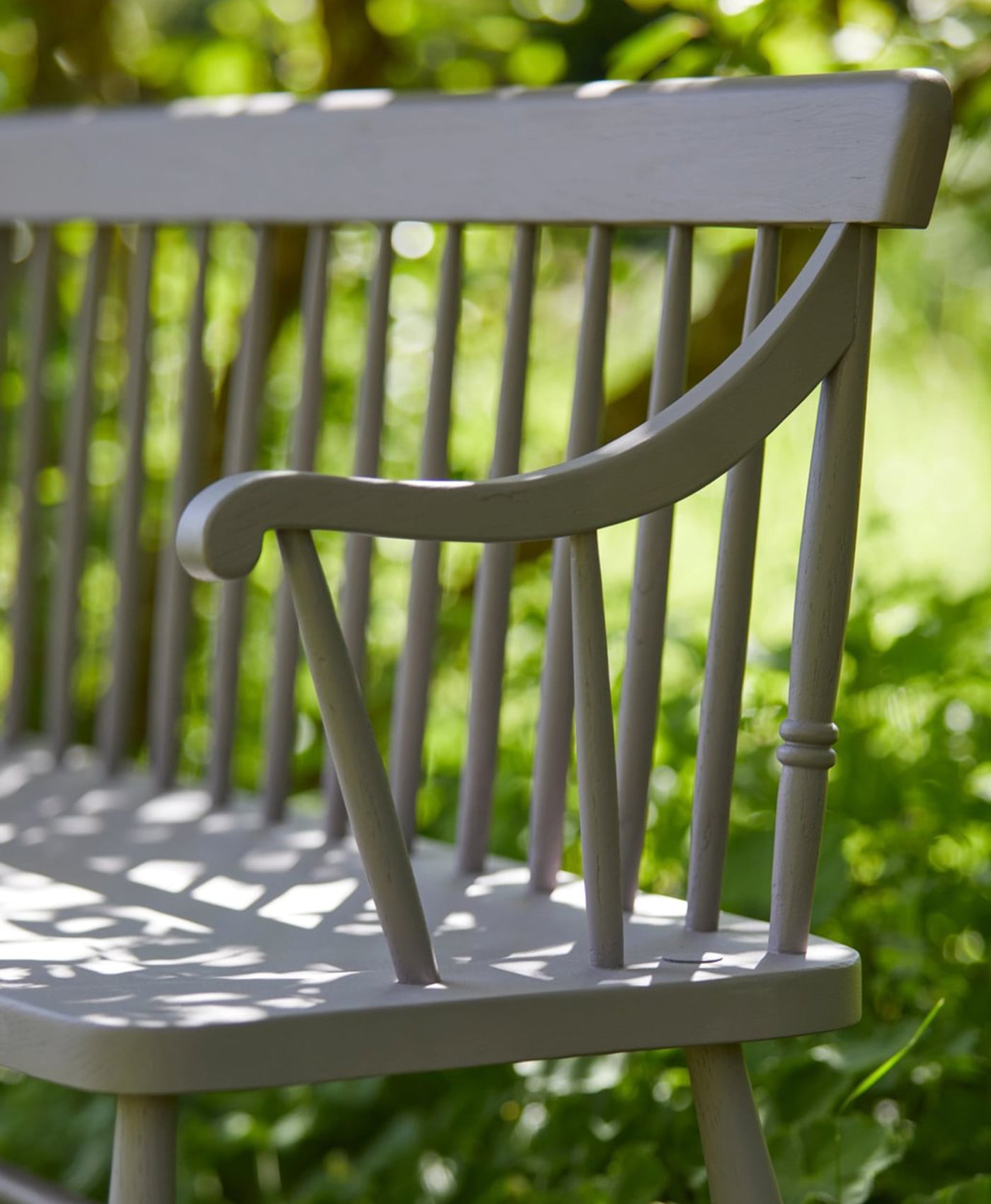 Neutral wooden chair with blurred green foliage in the background