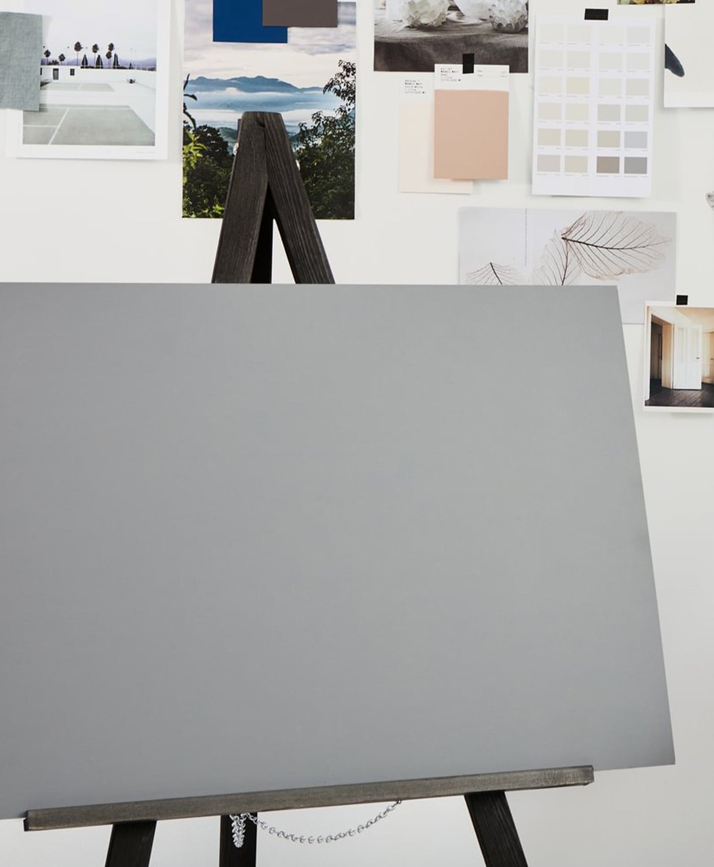 Gray canvas on an easel with a white wall and color swatches in the background
