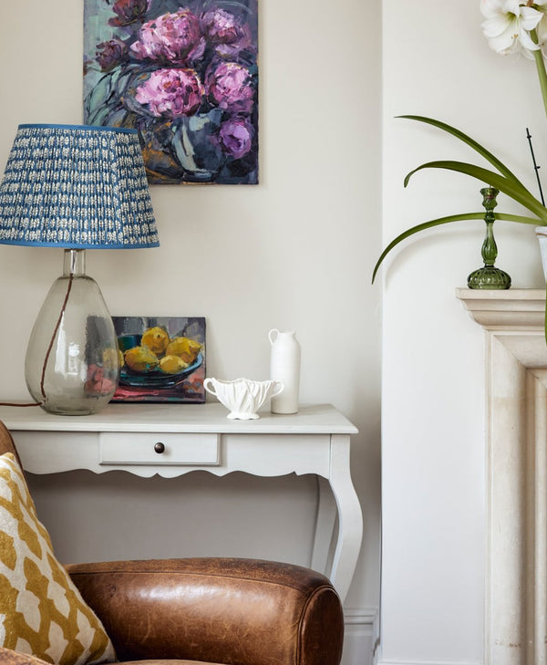 White living room interior with a white console table, brown leather chair, and decorative items.