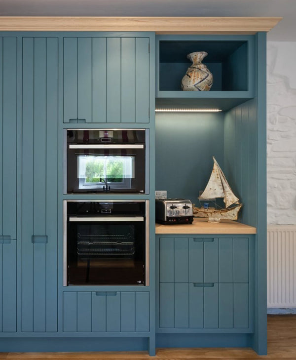 Blue kitchen cabinets with built-in appliances and decorative items.