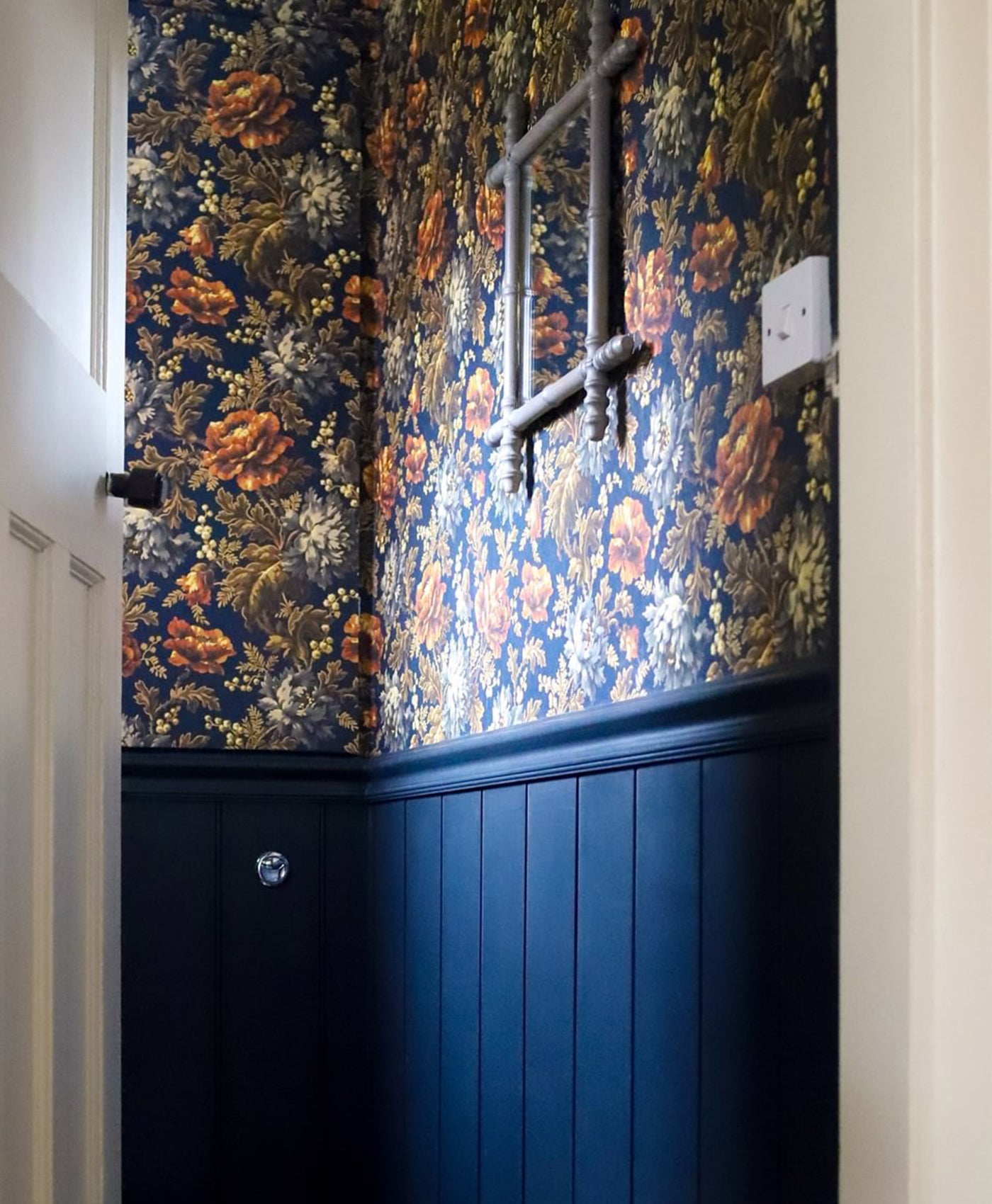 Wall with floral wallpaper and black panelling