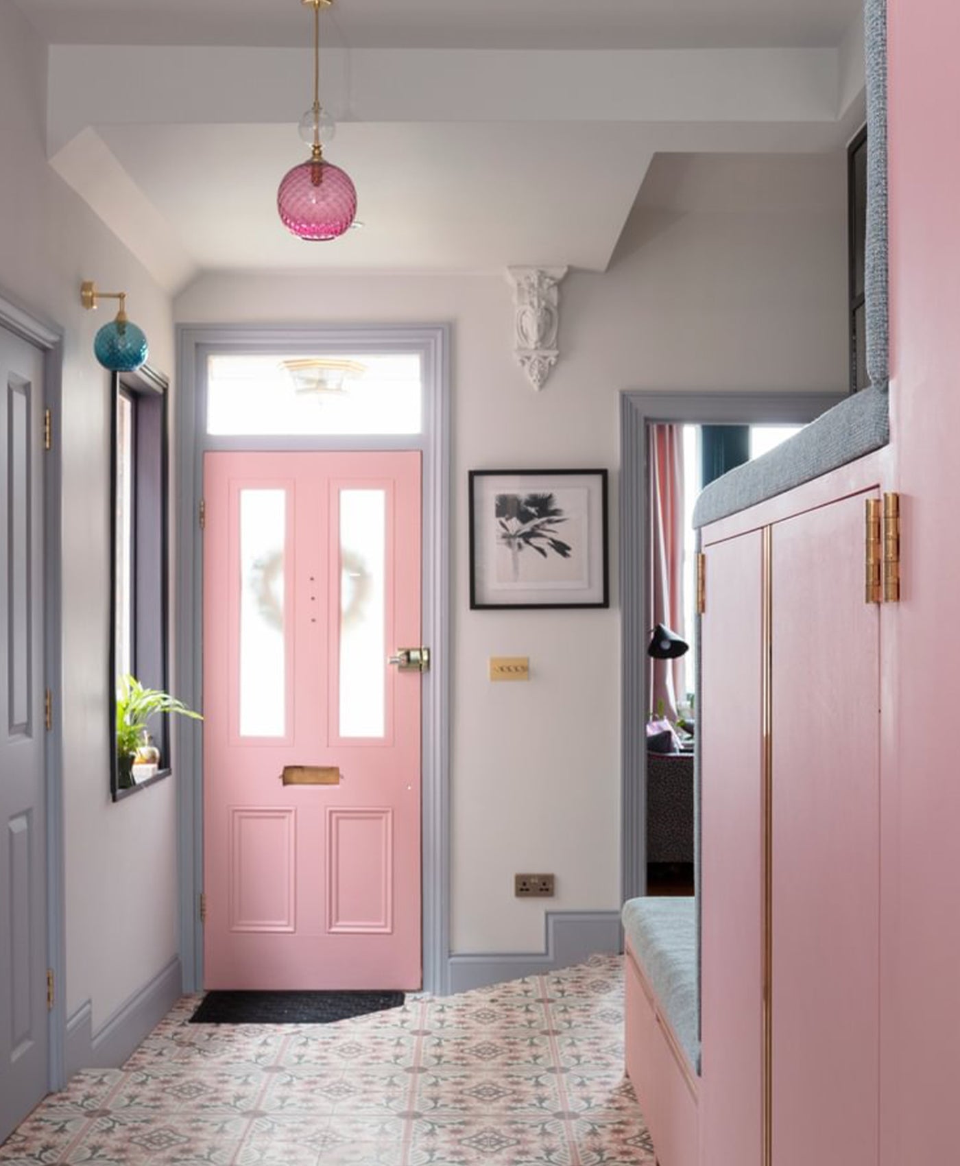 Foyer with a bubblegum pink door, pink wall, and decorative elements.