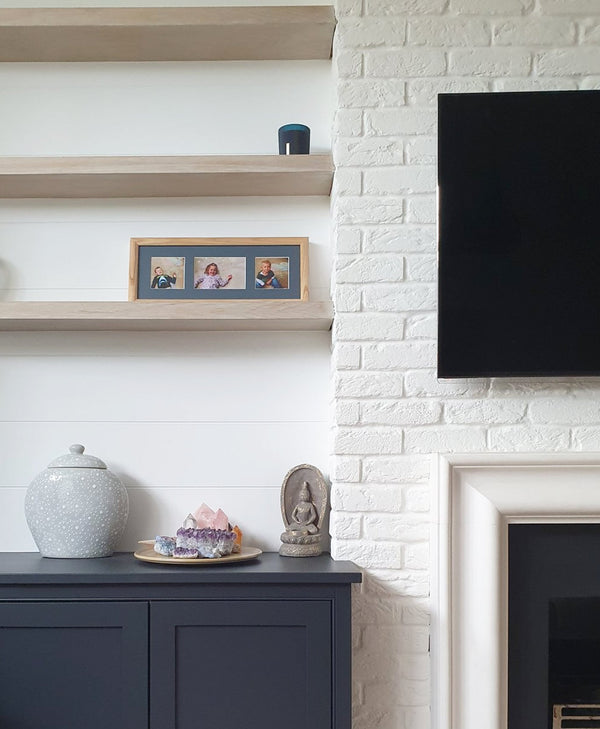 living room with whote brick painted chimney breast and navy painted cabinets