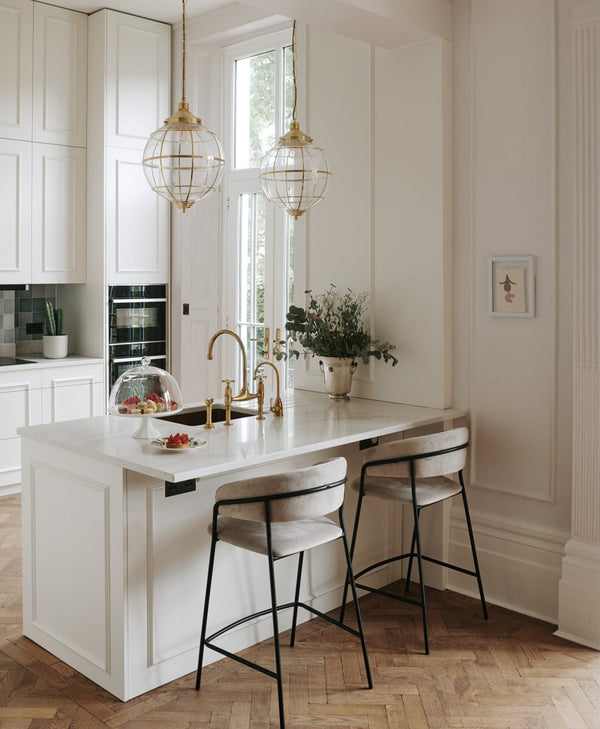 Modern kitchen with soft off-white island, bar stools, and pendant lights.