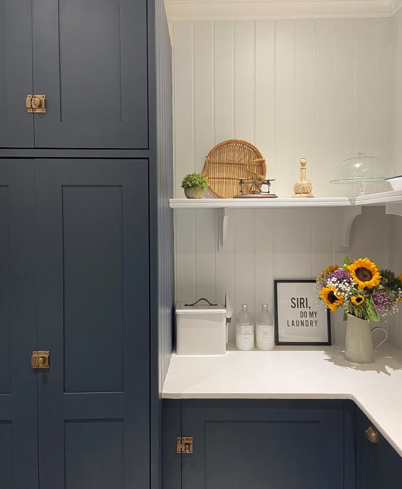 Modern kitchen with dark blue cabinets, white countertop, and decorative elements.