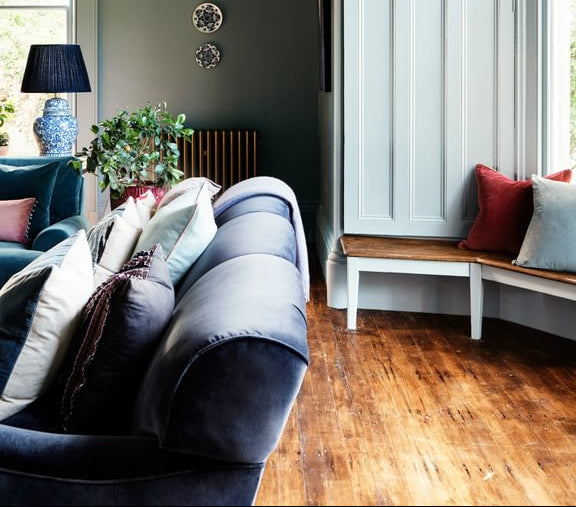 Mylands wood finishes - Living room with a blue sofa, wooden floor, and decorative elements.